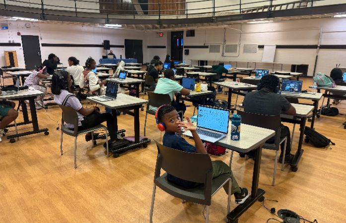  Students studying diligently, while one student waves at the camera